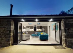 image of a limestone cottage in the evening. The bi-fold doors open onto a modern kitchen-diner.
