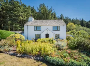 Cubben House, a whitewashed cottage surrounded by greenery and blue skies