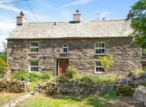 image of the front exterior elevation of a stone built family friendly cottage in the lake district