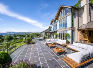 The patio and floor-to-ceiling windows at Post Knott Lodge, with views of Windermere lake and mountains