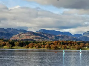 Windermere lake with a yacht sailing on it, and mountains in the background