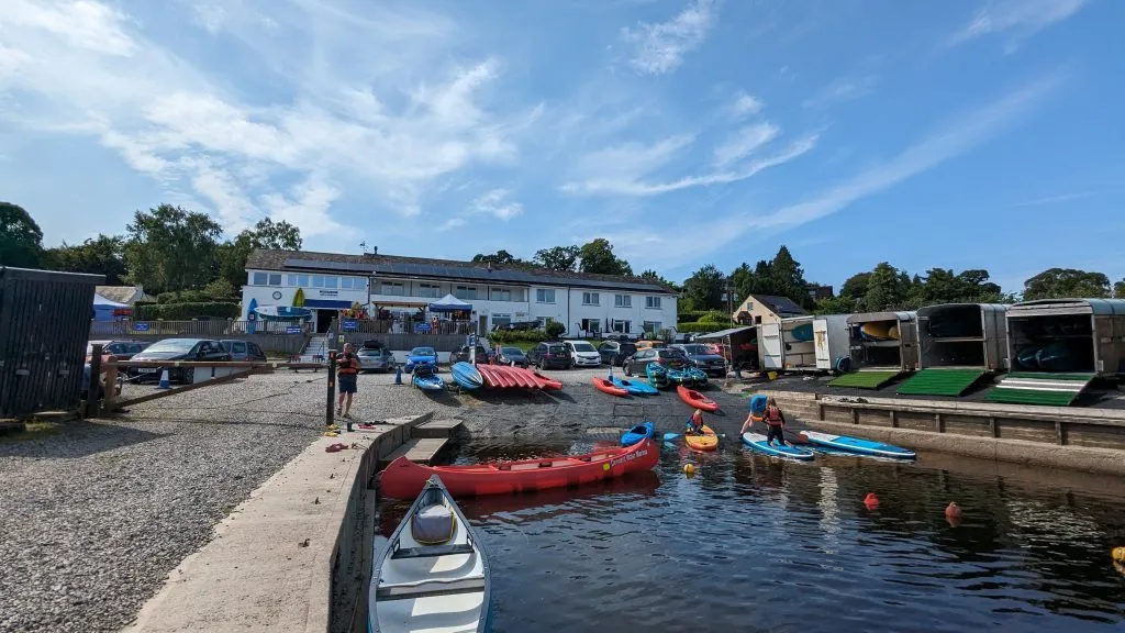 Image of the main building of Derwentwater marina showing boats buildings and a man in a wetsuit