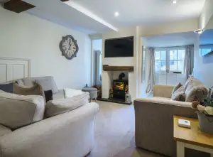 Image of the interior of Laburnum Cottage. photo shows sofa, table, cloak and wood fire.