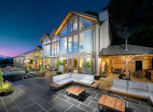 External of luxurious large lake district cottages, Post Knott Lodge, with multi-floor windows and an outside seating area