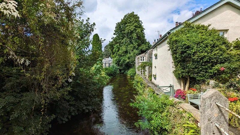 image of Cartmel village stream with trees and a house on the right