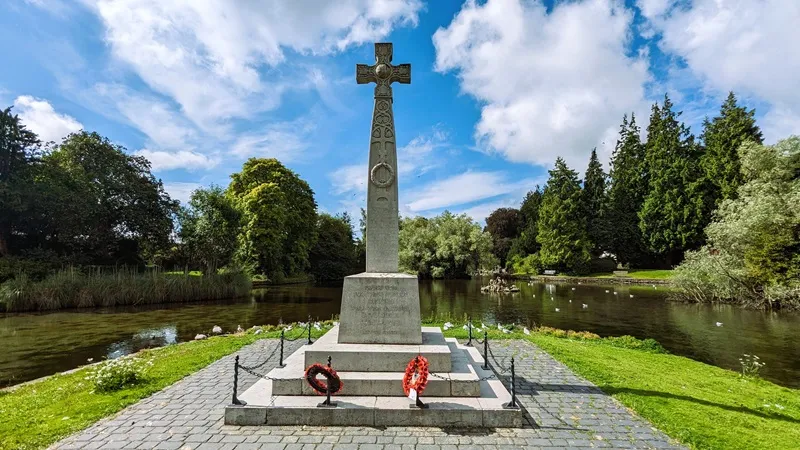 image of the pond at the ornamental gardens in grange over sands. photo also shows a war memorial