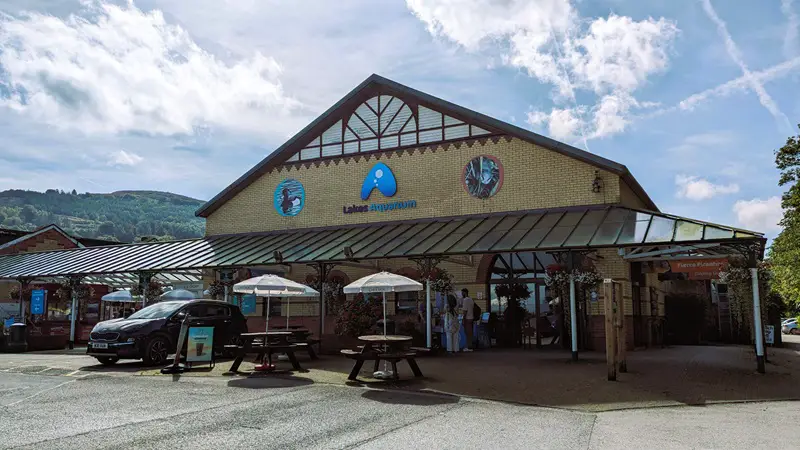 Image of the exterior of the Lakes Aquarium. photo shows the building in the centre of the frame with a couple about to enter the Aquarium