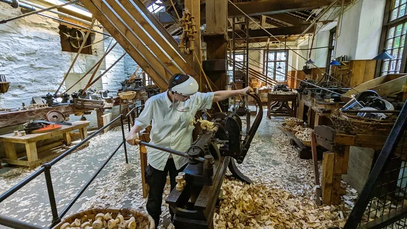 image of one of the machines for making bobbins being demonstrated by one of the workers at the mill