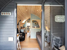 Image of a luxury lake district glamping pod with willow hurdles around it and in the background is a lake district fell with sheep grazing